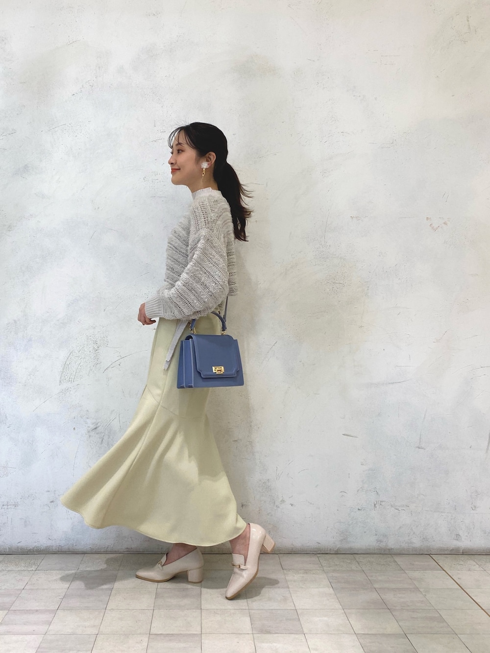 ホワイト系のローファー、イエロー系のスカート、ブルー系のハンドバッグを着用したレディースの冬コーディネートの3枚目の写真