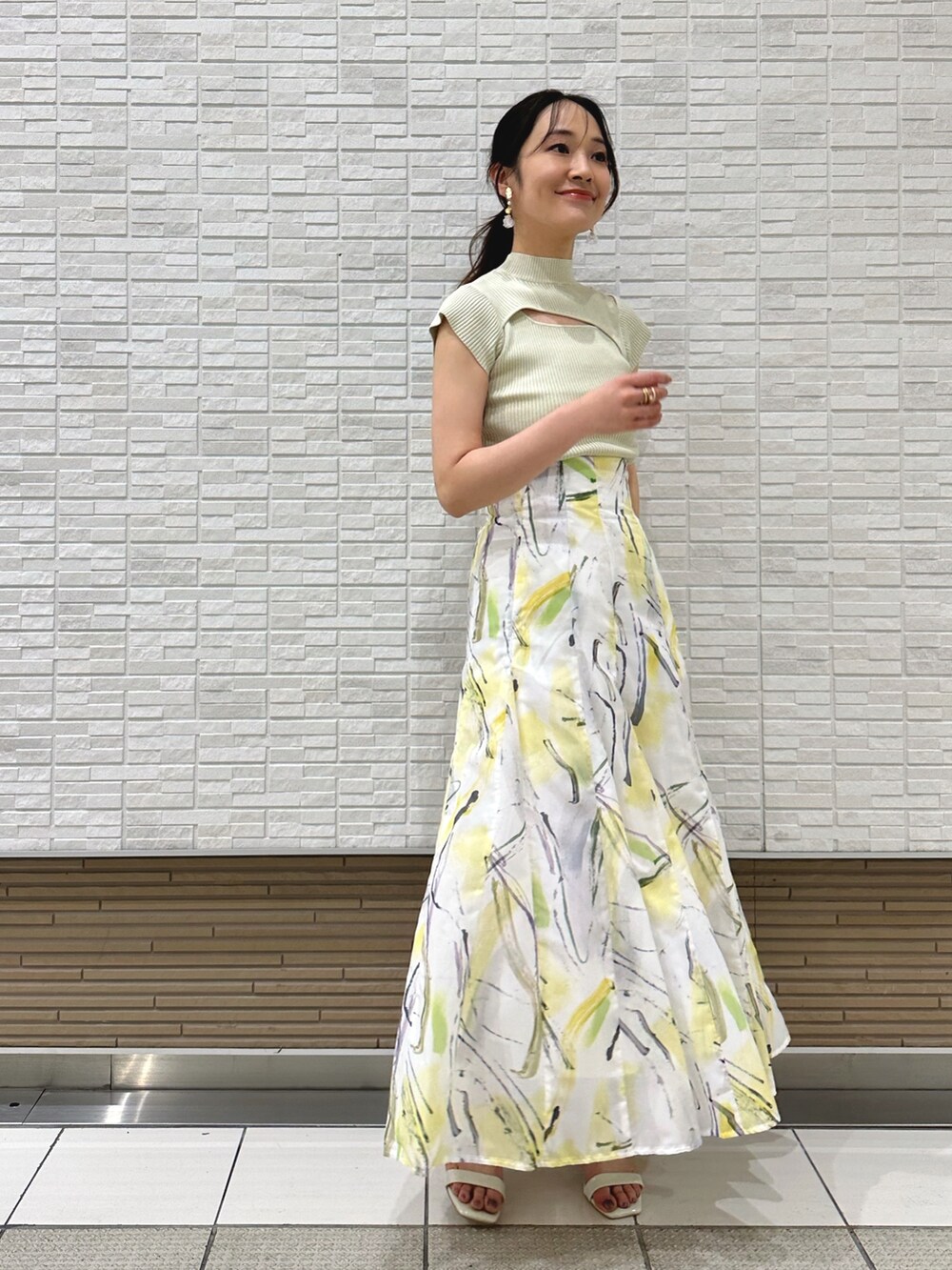 ホワイト系のキャミソール、ホワイト系のサンダル、イエロー系のスカートを着用したレディースの夏コーディネートの3枚目の写真