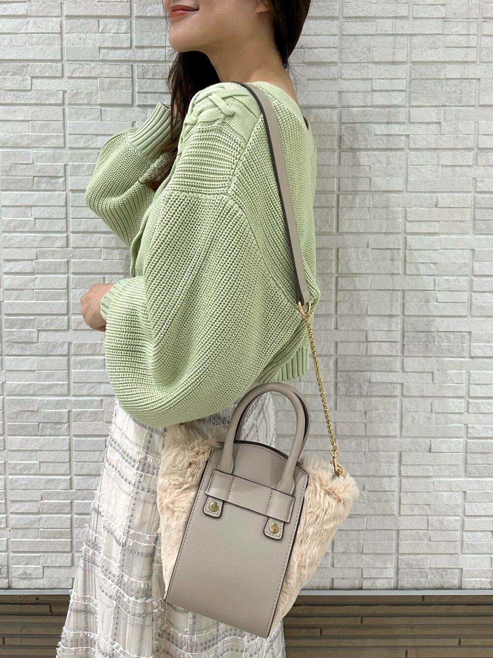 ホワイト系のハンドバッグ、グリーン系のカーディガン/ボレロ、ホワイト系のスカートを着用したレディースの秋コーディネートの7枚目の写真