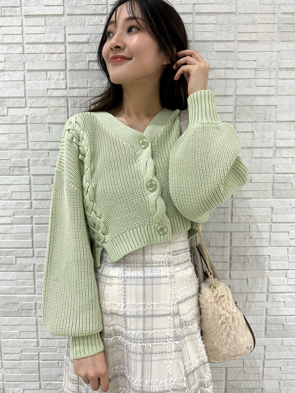 ホワイト系のハンドバッグ、グリーン系のカーディガン/ボレロ、ホワイト系のスカートを着用したレディースの秋コーディネートの5枚目の写真