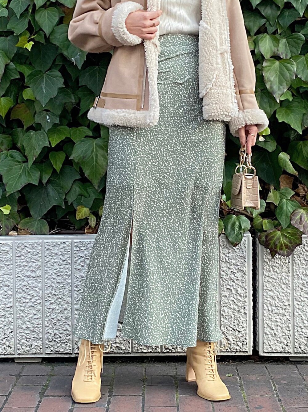 ベージュ系のムートンコート、ホワイト系のニット/セーター、ベージュ系のスカートを着用したレディースの冬コーディネートの4枚目の写真