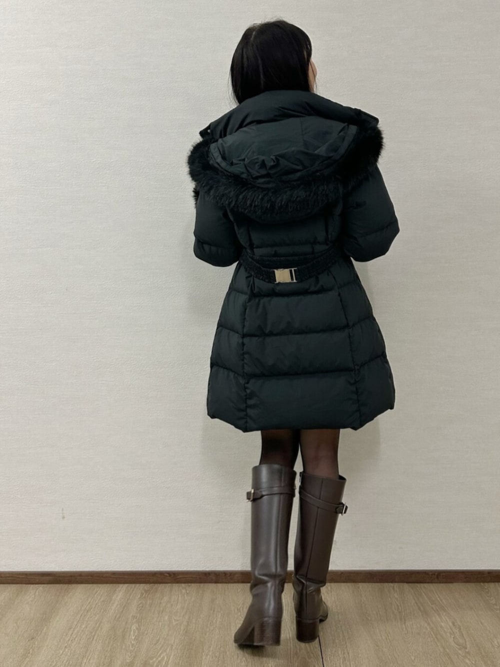 グリーン系のワンピース、ブラウン系のブーツ、ブラック系のダウンジャケット/コートを着用したレディースの冬コーディネートの3枚目の写真