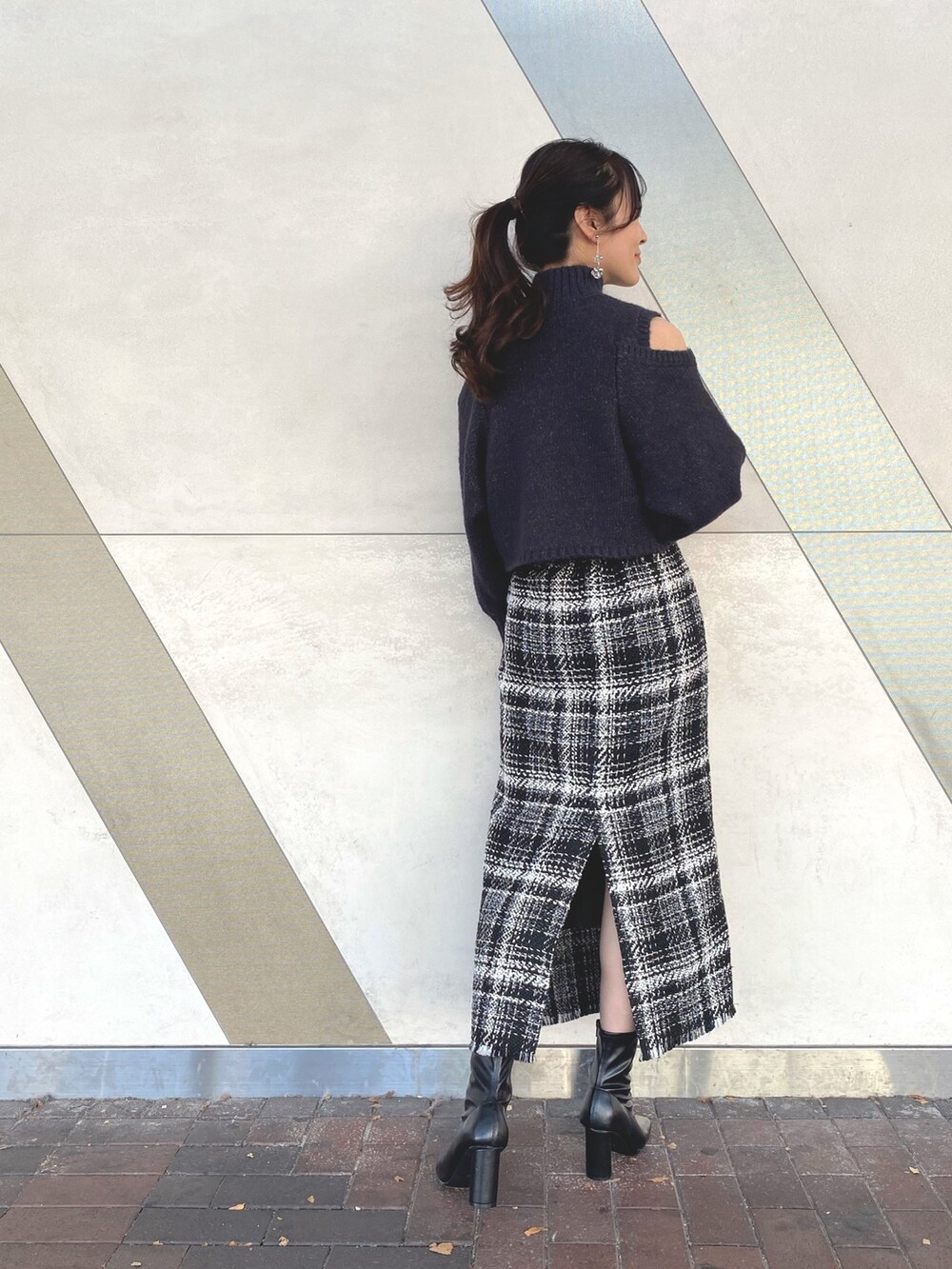 グレー系のニット/セーター、ブラック系のスカート、ブラック系のブーツを着用したレディースの秋コーディネートの3枚目の写真