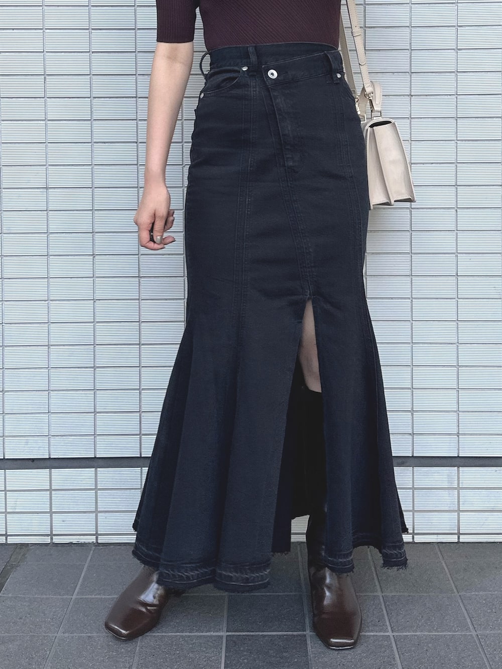 ブラウン系のニット/セーター、ブラック系のデニムスカート、ベージュ系のショルダーバッグを着用したレディースの秋コーディネートの6枚目の写真