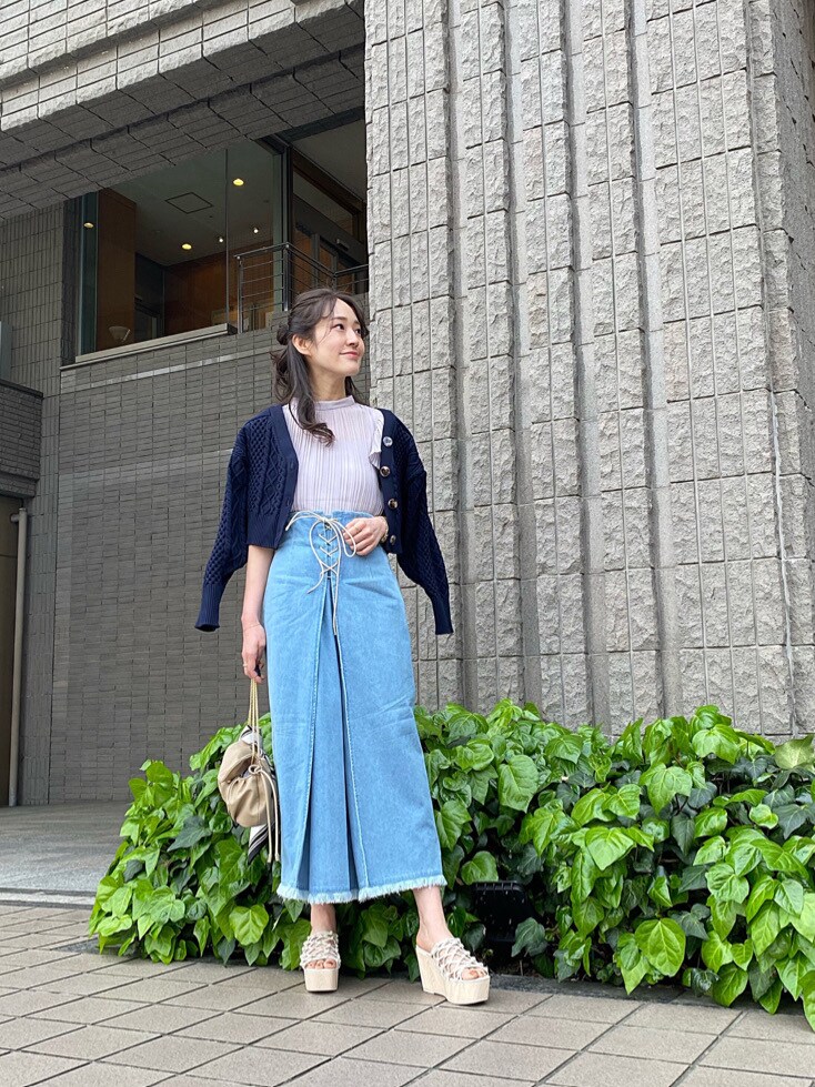 ベージュ系のクラッチバッグ、ホワイト系のサンダル、ブルー系のスカートを着用したレディースの春コーディネートの2枚目の写真