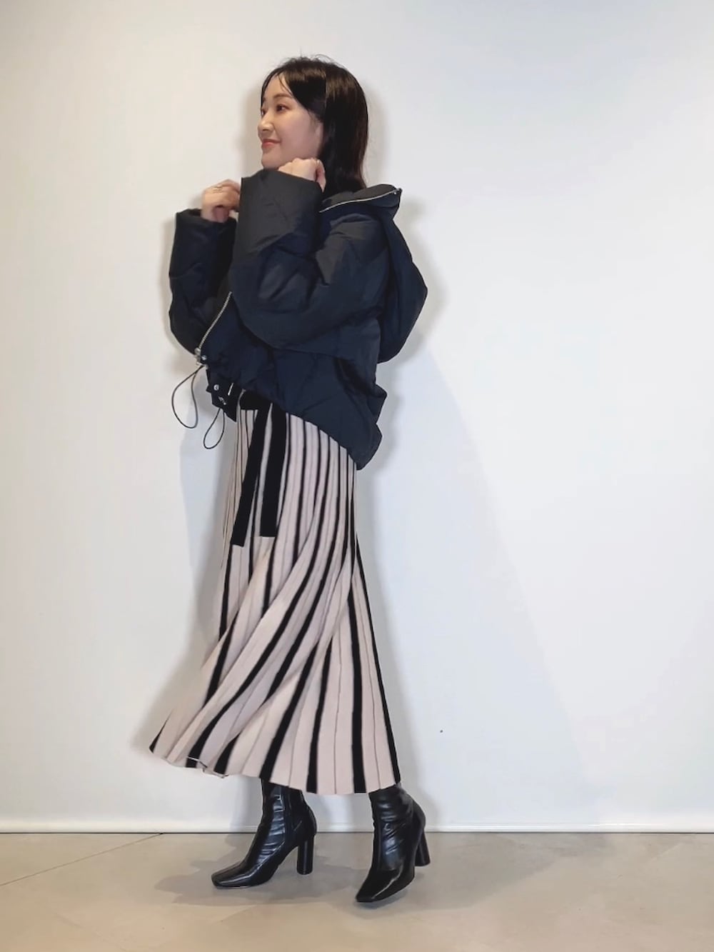 ブラック系のブーツ、ブラック系のワンピース、ブラック系のダウンジャケット/コートを着用したレディースの冬コーディネートの2枚目の写真