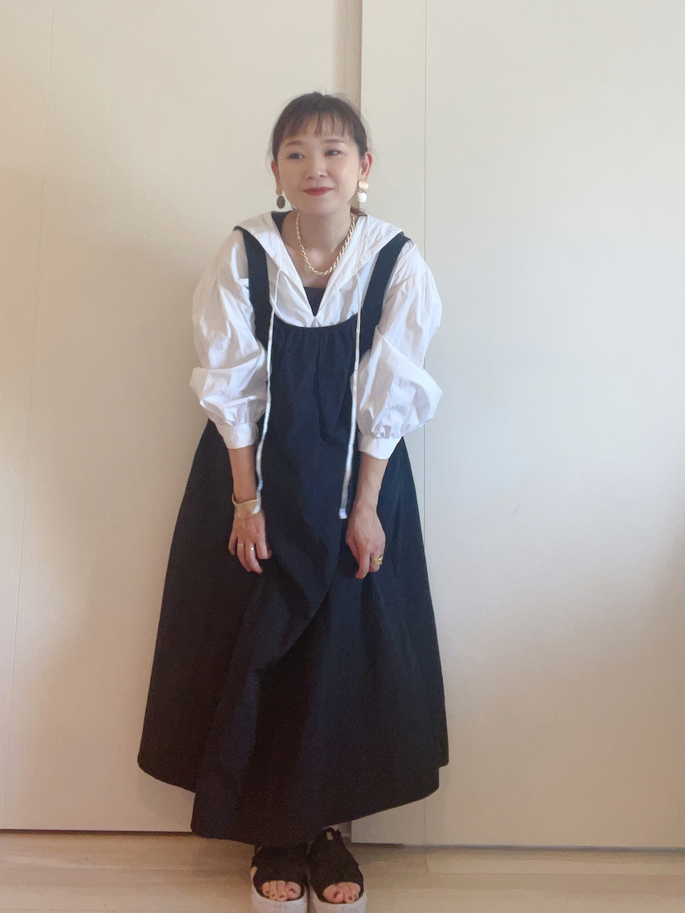 ブラック系のワンピース、ホワイト系のシャツ/ブラウス、ブラック系のサンダルを着用したレディースの春コーディネートの2枚目の写真