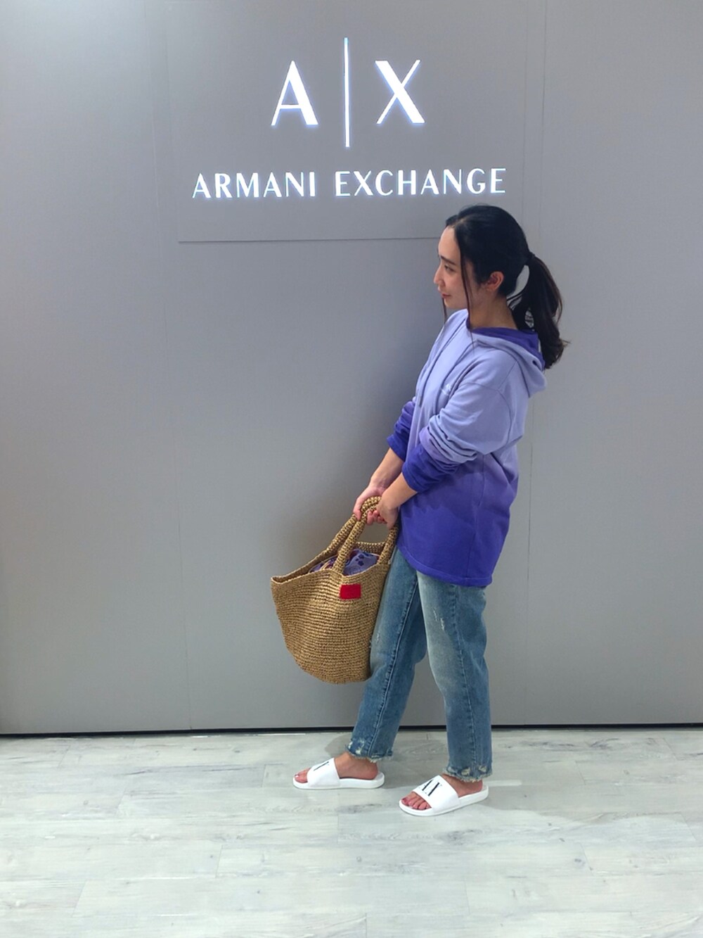 ベージュ系のトートバッグ、ホワイト系のサンダル、ブルー系のデニムパンツを着用したレディースの春コーディネートの2枚目の写真