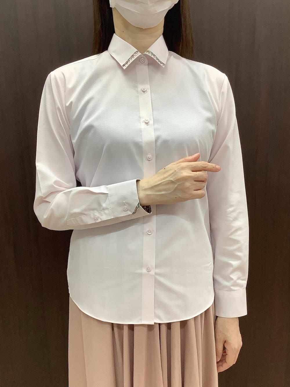 ピンク系のビジネスシャツ、ブルー系のベストを着用したレディースの秋コーディネートの3枚目の写真