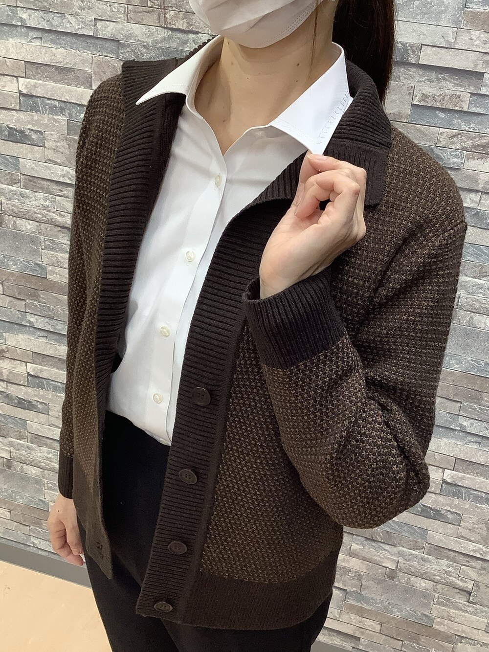 ブラック系のパンツ、ブラウン系のカーディガン/ボレロ、ホワイト系のビジネスシャツを着用したレディースの秋コーディネートの2枚目の写真