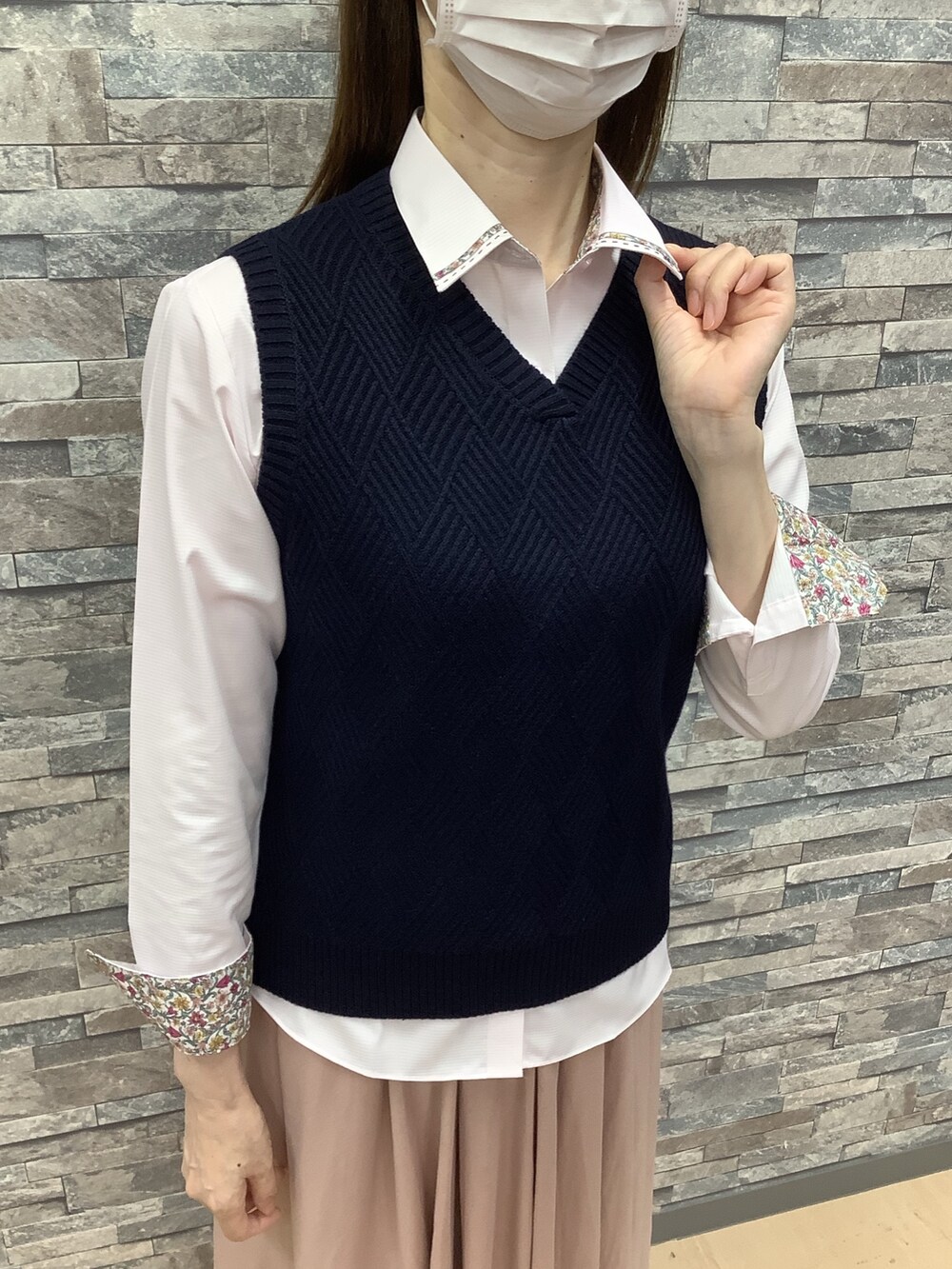 ピンク系のビジネスシャツ、ブルー系のベストを着用したレディースの秋コーディネートの2枚目の写真