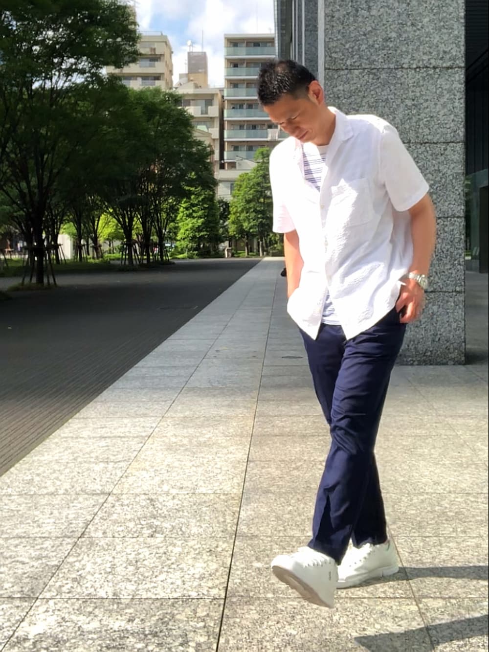 ホワイト系のスニーカー、ブラウン系のチノパンツ、ホワイト系のシャツ/ブラウスを着用したメンズの夏コーディネートの3枚目の写真