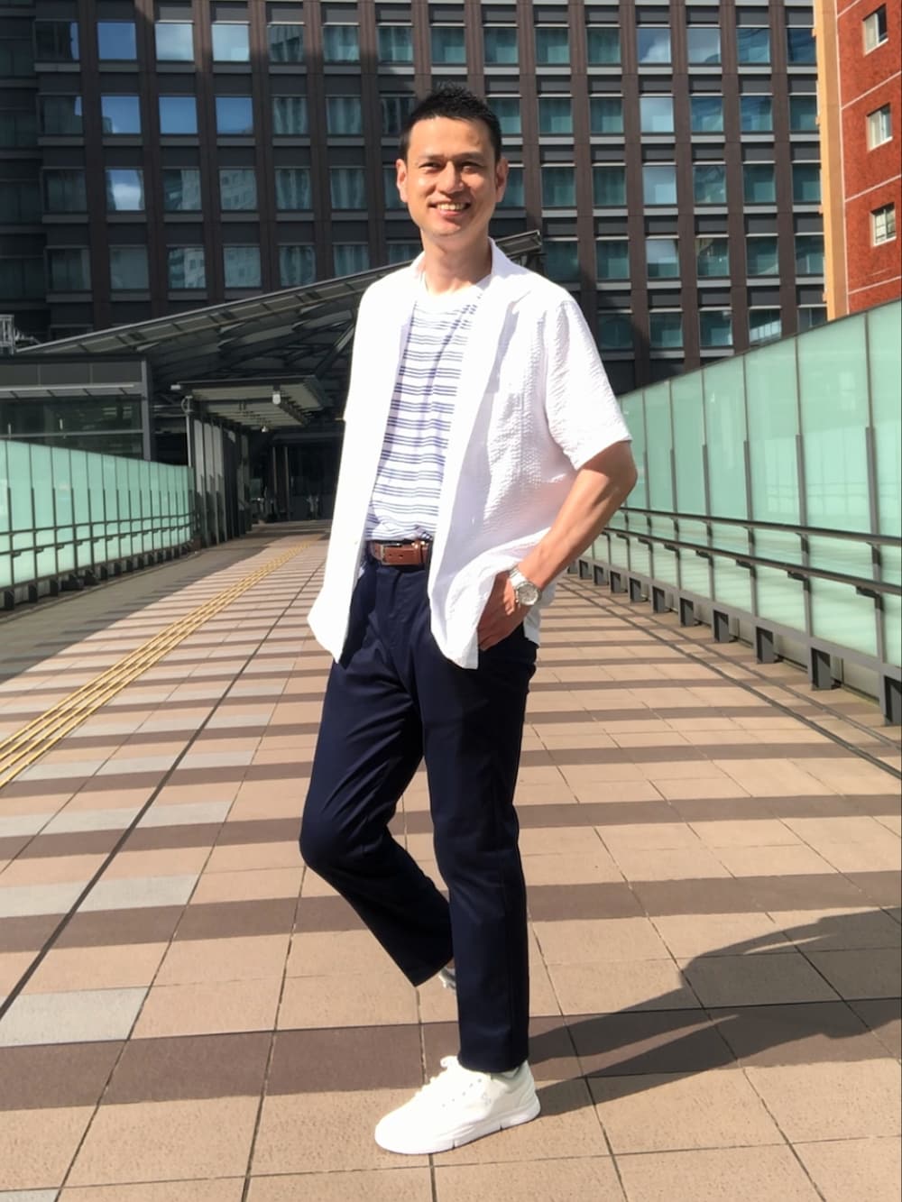 ホワイト系のスニーカー、ブラウン系のチノパンツ、ホワイト系のシャツ/ブラウスを着用したメンズの夏コーディネートの4枚目の写真