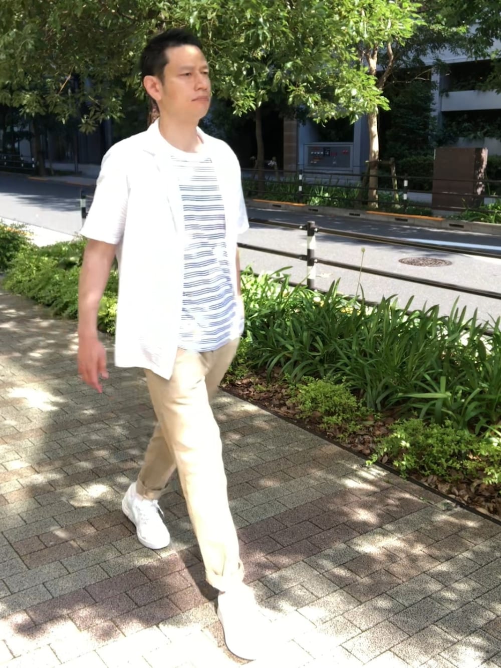 ホワイト系のスニーカー、ベージュ系のチノパンツ、ブルー系のTシャツ/カットソーを着用したメンズの夏コーディネートの2枚目の写真