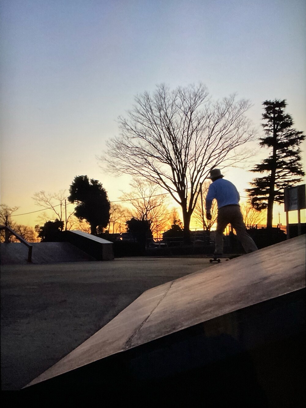 ホワイト系のスウェット、ベージュ系のチノパンツ、ブラック系のスニーカーを着用したメンズの夏コーディネートの2枚目の写真