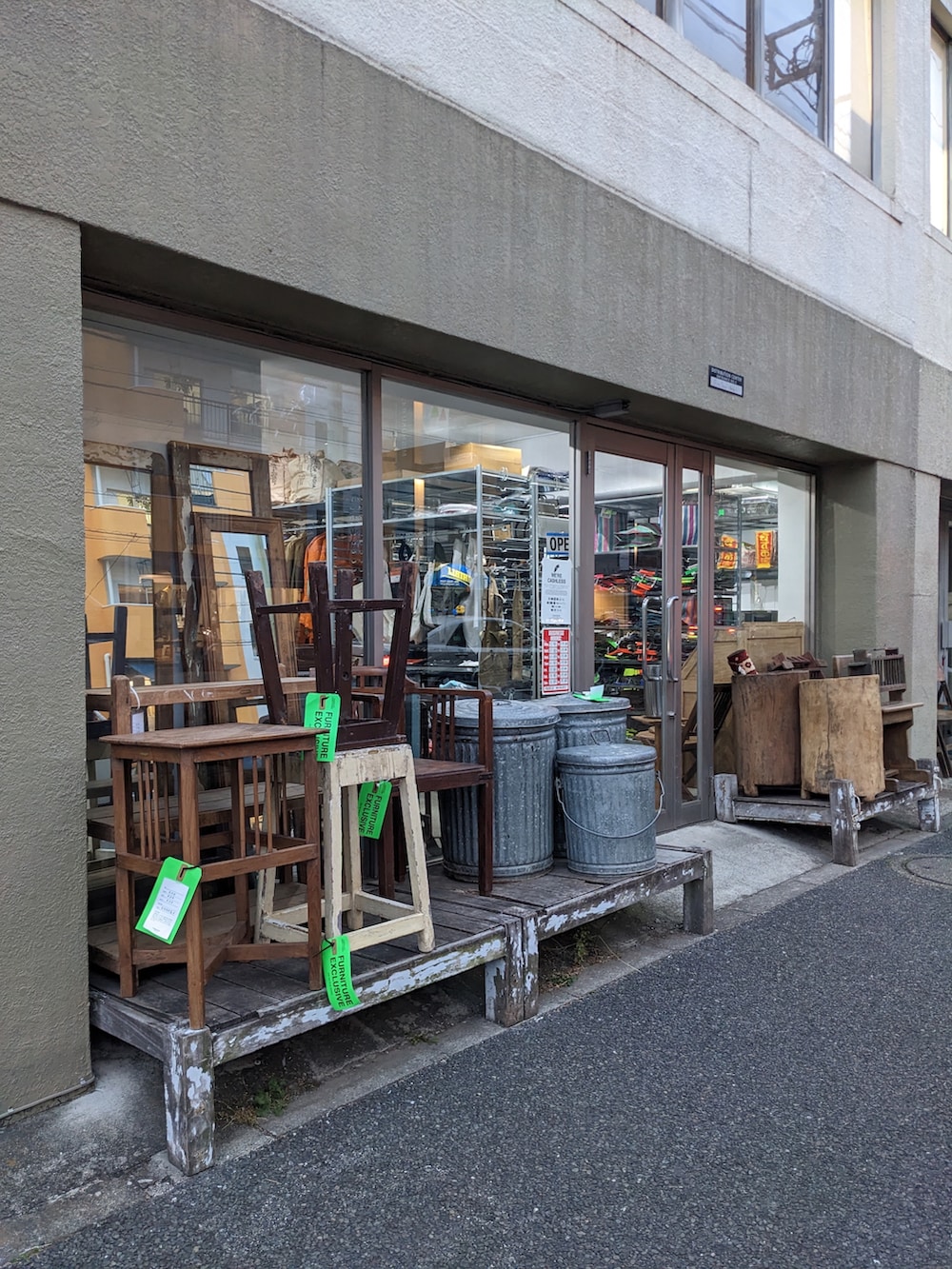 ブラウン系のニット/セーター、その他のダウンジャケット/コート、ベージュ系のチノパンツを着用したメンズの春コーディネートの2枚目の写真