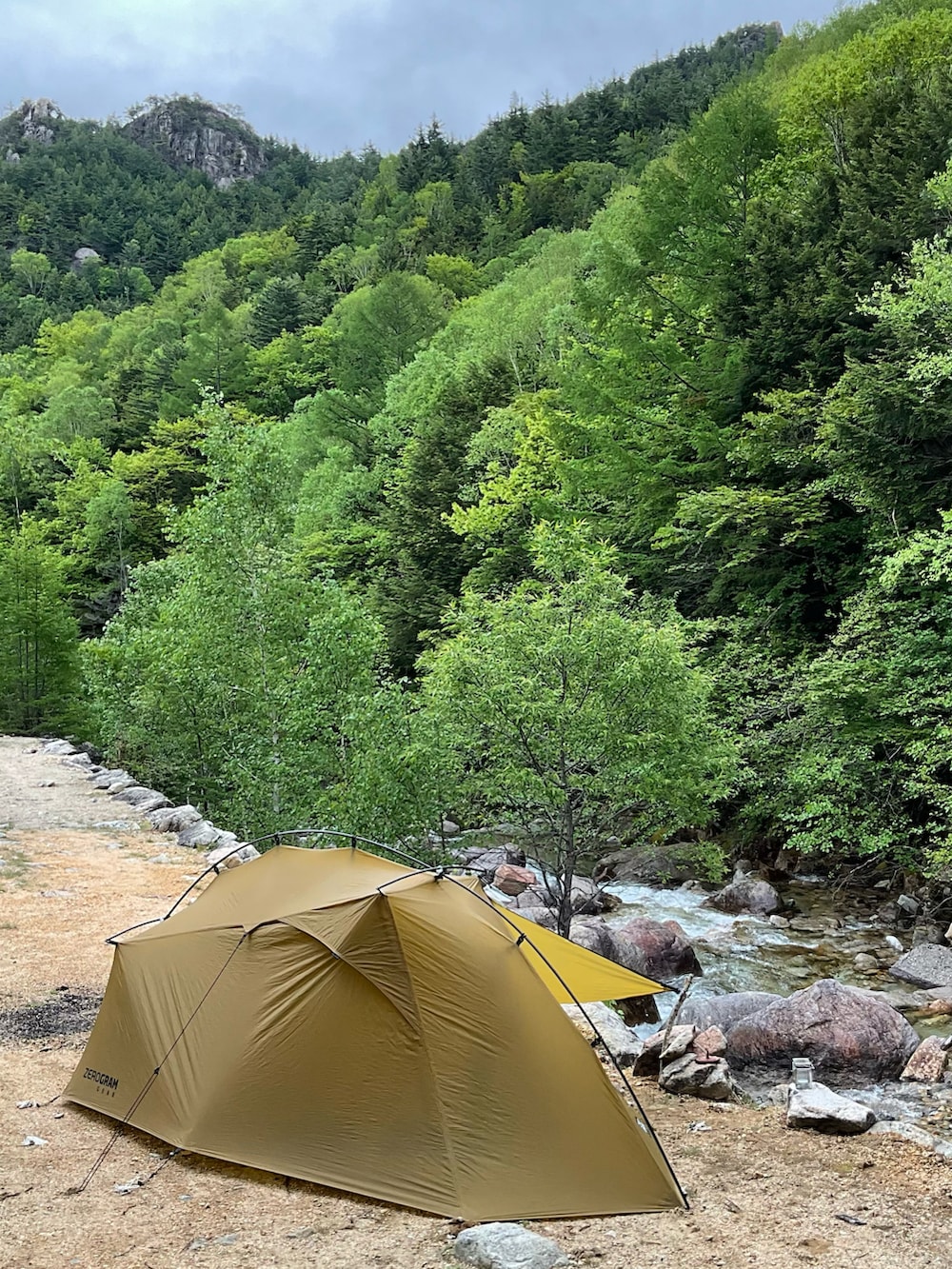 グリーン系のシャツ/ブラウス、ベージュ系のブーツ、グリーン系のマウンテンパーカーを着用したメンズの夏コーディネートの2枚目の写真