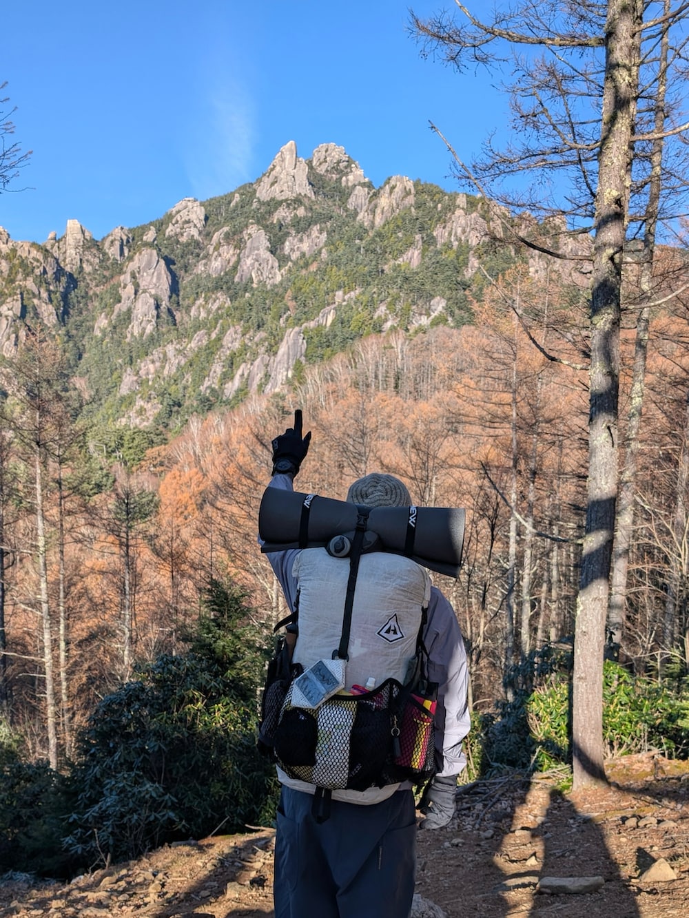 グレー系のマウンテンパーカー、ブルー系のパンツ、ホワイト系のバックパック/リュックを着用したメンズの秋コーディネートの2枚目の写真