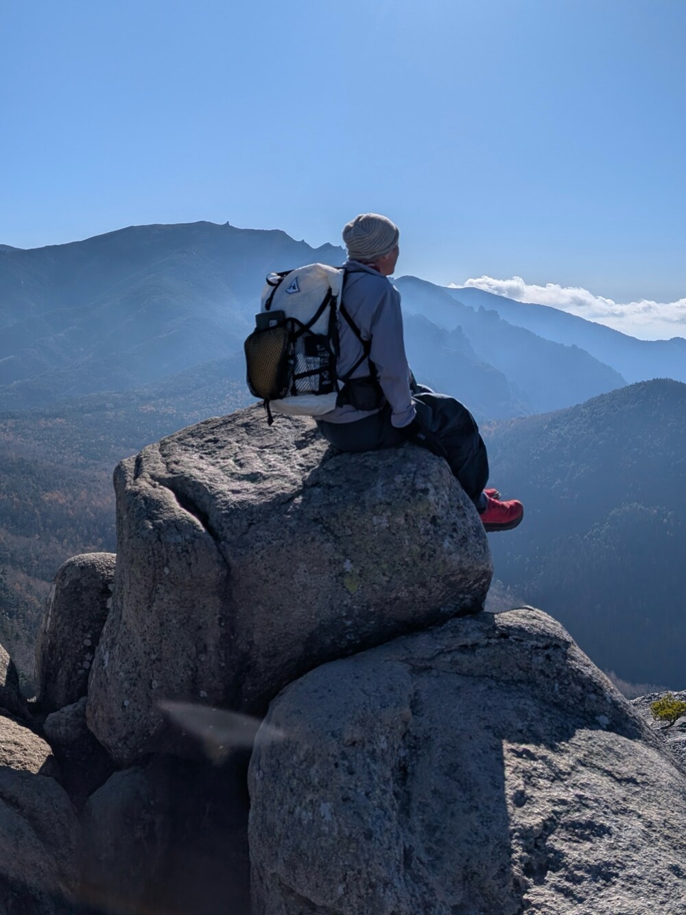 グレー系のマウンテンパーカー、ブルー系のパンツ、ホワイト系のバックパック/リュックを着用したメンズの秋コーディネートの5枚目の写真