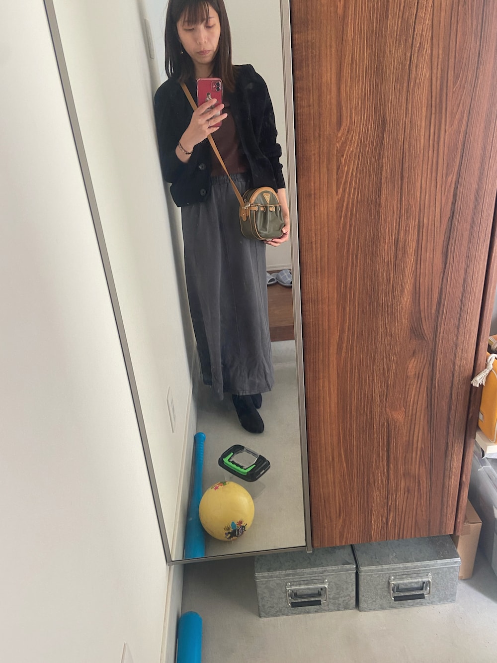 グレー系のスカート、ブラウン系のTシャツ/カットソー、ブラック系のカーディガン/ボレロを着用したレディースの秋コーディネートの2枚目の写真