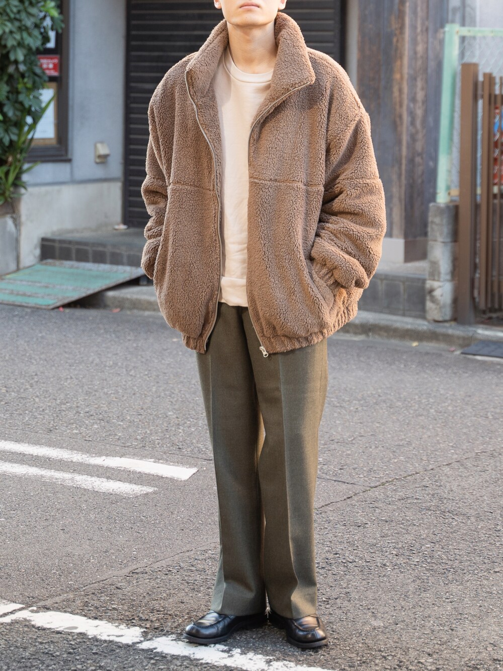 ブラウン系のブルゾン、グリーン系のスラックスを着用したメンズの秋コーディネートの2枚目の写真
