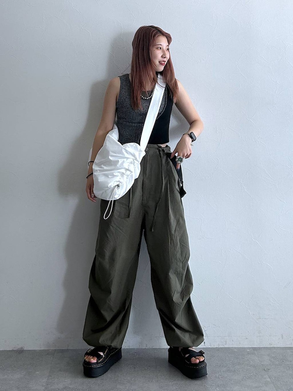 グリーン系のその他パンツ、ホワイト系のショルダーバッグ、ブラック系のタンクトップを着用したレディースの秋コーディネートの2枚目の写真