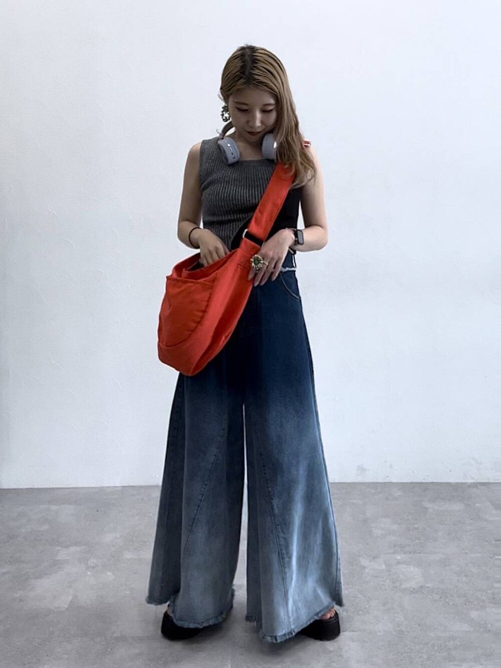ブルー系のデニムパンツ、ブラック系のタンクトップ、オレンジ系のショルダーバッグを着用したレディースの夏コーディネートの2枚目の写真
