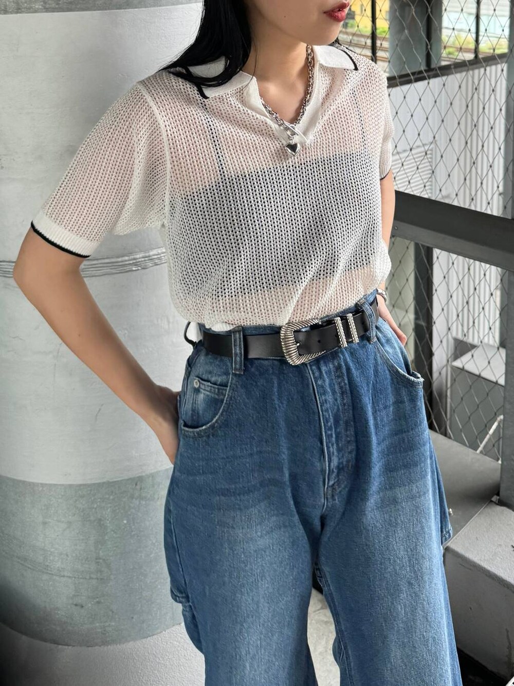 ブルー系のデニムパンツ、ホワイト系のニット/セーター、ブラック系のベルトを着用したレディースの春コーディネートの2枚目の写真