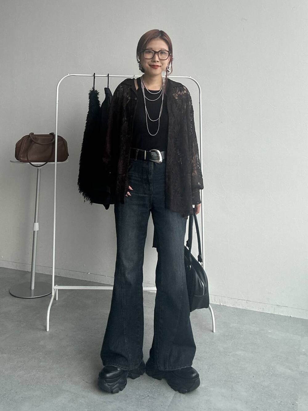 ブラック系のスニーカー、ブルー系のデニムパンツ、ブラウン系のシャツ/ブラウスを着用したレディースの秋コーディネートの3枚目の写真