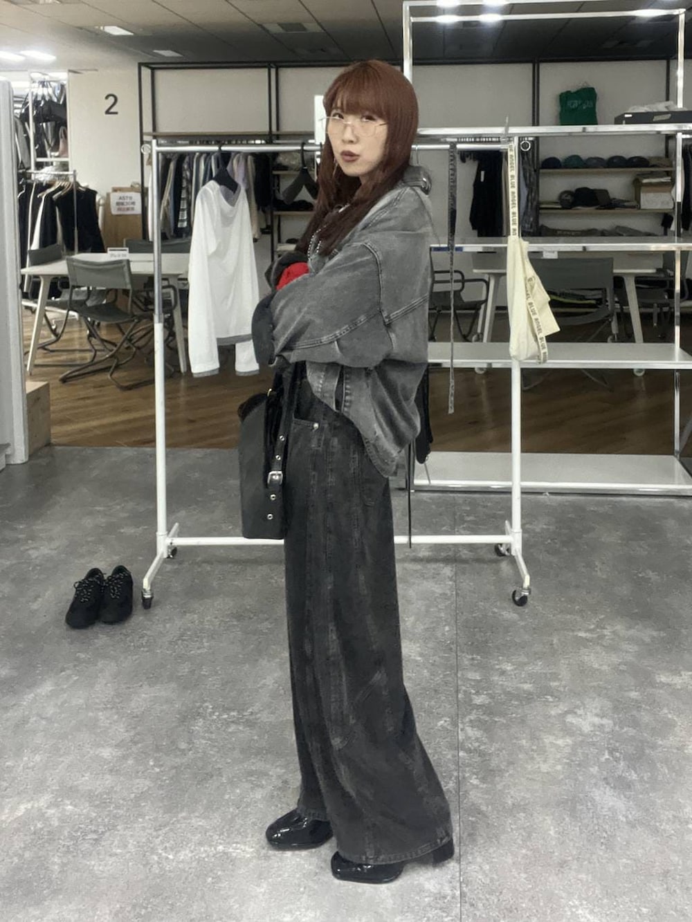 ブラック系のハンドバッグ、ブラック系のブルゾン、ブラック系のデニムパンツを着用したレディースの冬コーディネートの4枚目の写真