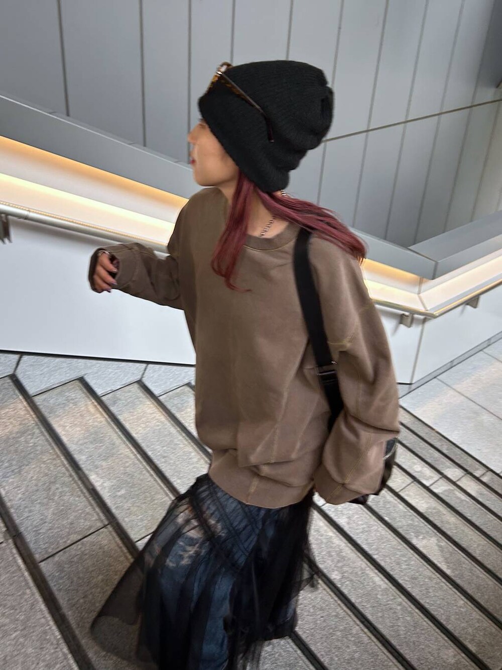 ブラウン系のスウェット、ブルー系のデニムパンツ、ブラック系のブーツを着用したレディースの秋コーディネートの6枚目の写真