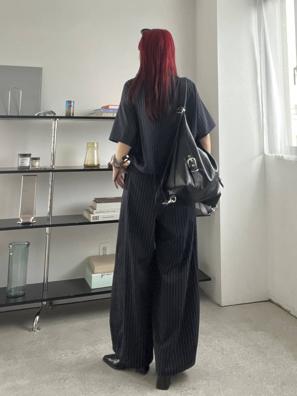 ブラック系のショルダーバッグ、ブラック系のキャミソール、ブルー系のスラックスを着用したレディースの夏コーディネートの4枚目の写真