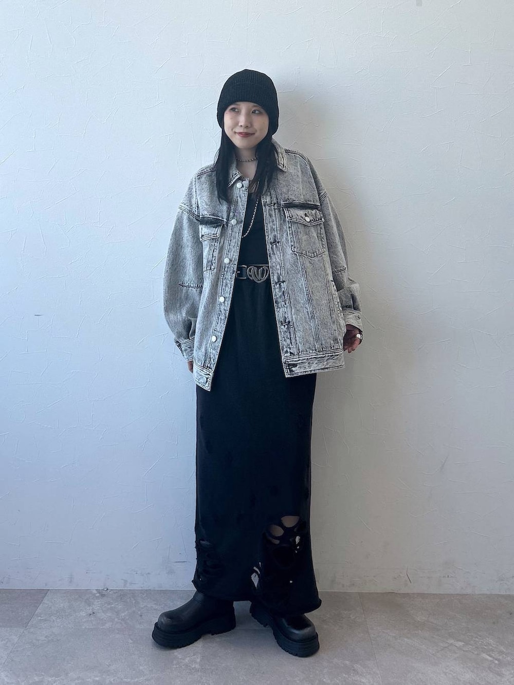 グレー系のデニムジャケット、ブラック系のブーツ、ブラック系のスカートを着用したレディースの春コーディネートの2枚目の写真