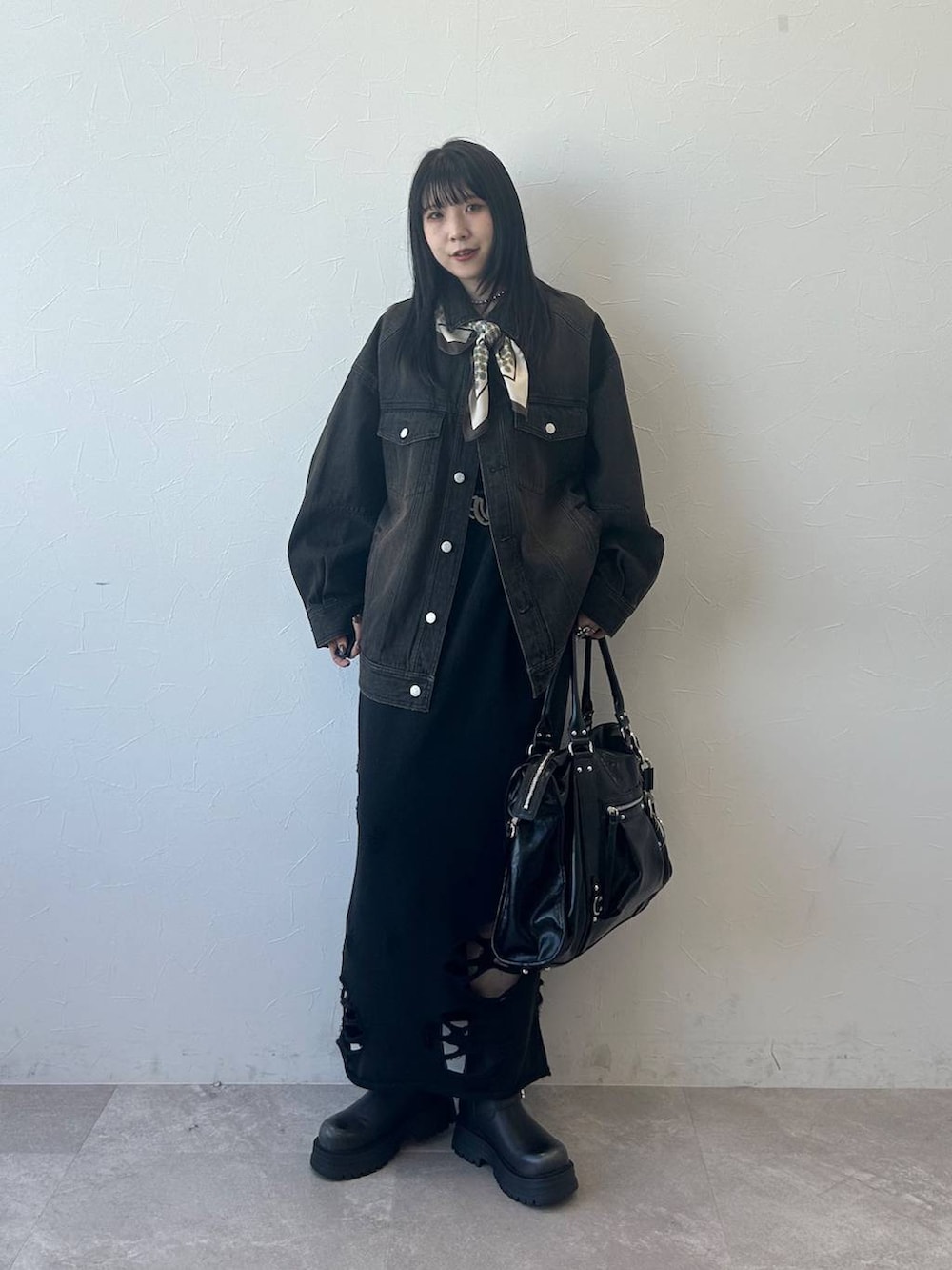 ブラック系のデニムジャケット、ブラック系のブーツ、ブラック系のスカートを着用したレディースの春コーディネートの3枚目の写真