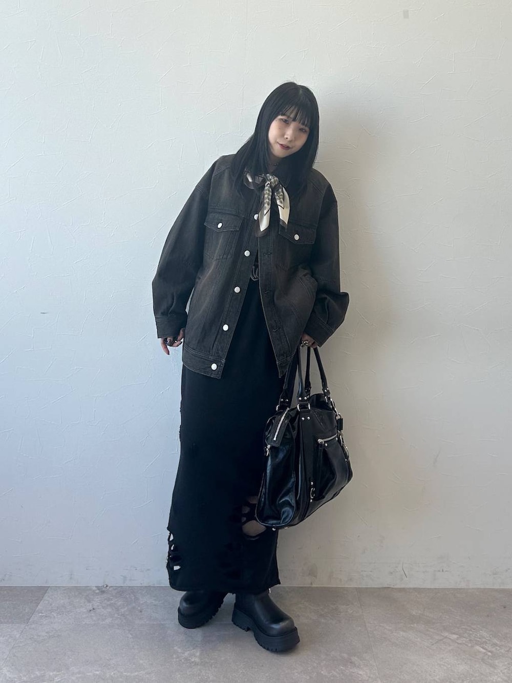 ブラック系のデニムジャケット、ブラック系のブーツ、ブラック系のスカートを着用したレディースの春コーディネートの2枚目の写真