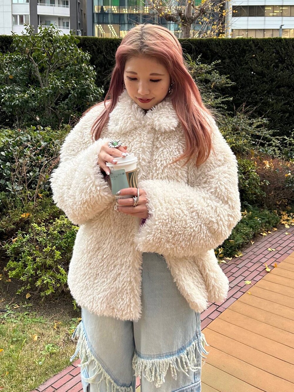 パープル系のニット/セーター、ブラック系のスニーカー、ホワイト系のその他アウターを着用したレディースの冬コーディネートの2枚目の写真