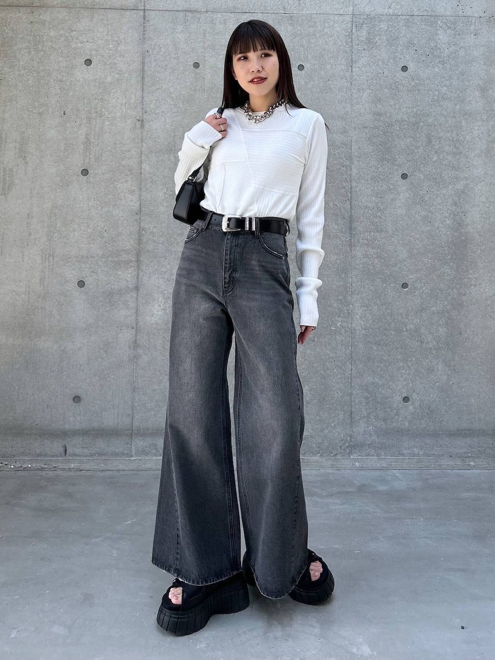 ホワイト系のニット/セーター、ブラック系のスニーカー、ブラック系のデニムパンツを着用したレディースの春コーディネートの2枚目の写真