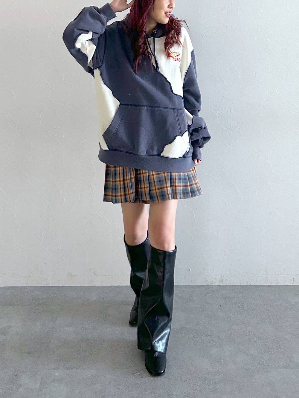 ブラック系のブーツ、ブルー系のパーカー、レッド系のスカートを着用したレディースの秋コーディネートの3枚目の写真