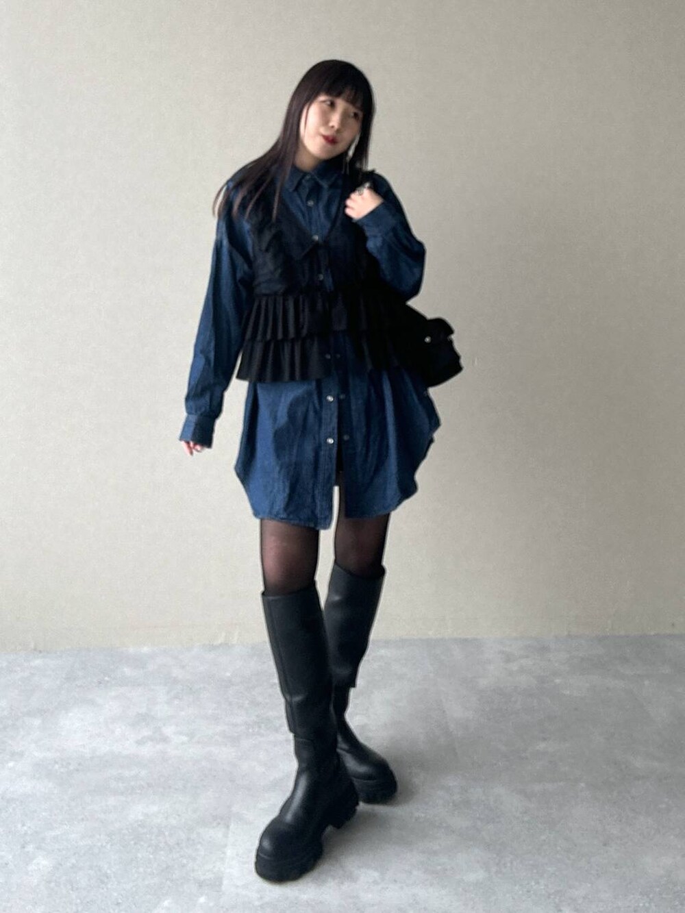 ブラック系のショルダーバッグ、ブルー系のシャツ/ブラウス、ブラック系のブーツを着用したレディースの春コーディネートの5枚目の写真