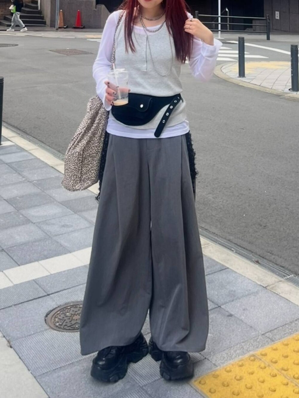 ブラック系のスニーカー、グレー系のタンクトップ、グレー系のスラックスを着用したレディースの夏コーディネートの3枚目の写真