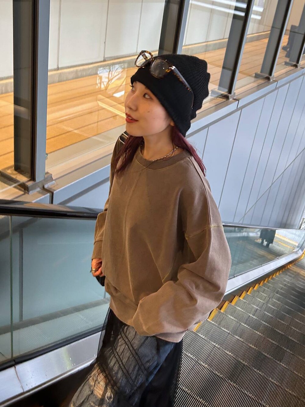 ブラウン系のスウェット、ブルー系のデニムパンツ、ブラック系のブーツを着用したレディースの秋コーディネートの5枚目の写真