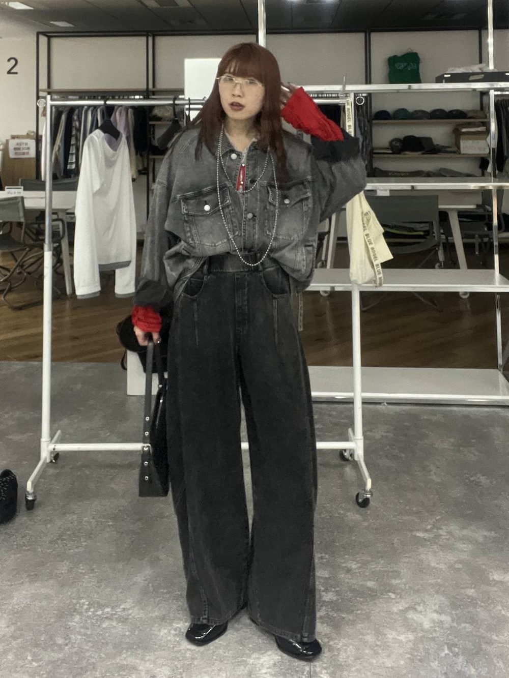 ブラック系のハンドバッグ、ブラック系のブルゾン、ブラック系のデニムパンツを着用したレディースの冬コーディネートの2枚目の写真