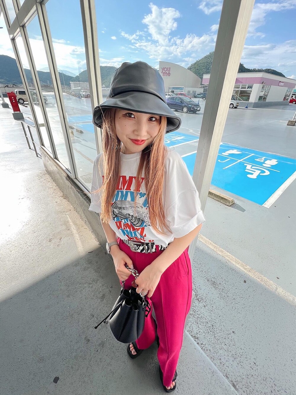 ブラック系のサンダル、ピンク系のスラックス、ブラック系のショルダーバッグを着用したレディースの夏コーディネートの2枚目の写真