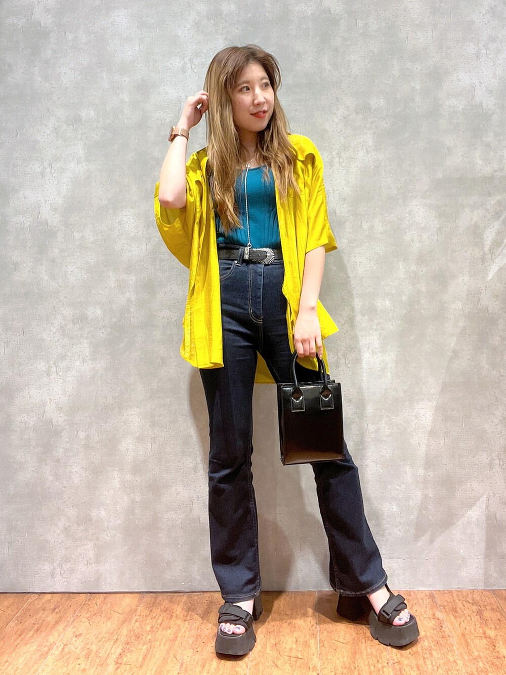 イエロー系のシャツ/ブラウス、グリーン系のタンクトップ、ブラック系のデニムパンツを着用したレディースの夏コーディネートの2枚目の写真