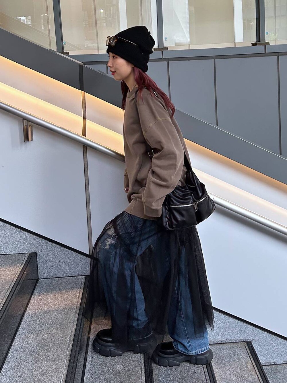 ブラウン系のスウェット、ブルー系のデニムパンツ、ブラック系のブーツを着用したレディースの秋コーディネートの3枚目の写真