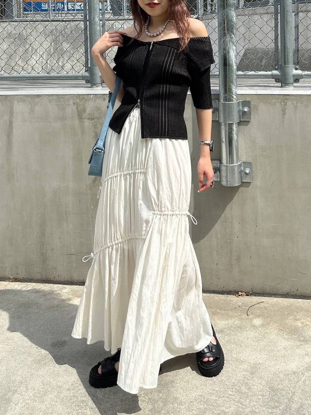 ブラック系のサンダル、ホワイト系のスカート、ブラック系のニット/セーターを着用したレディースの夏コーディネートの3枚目の写真