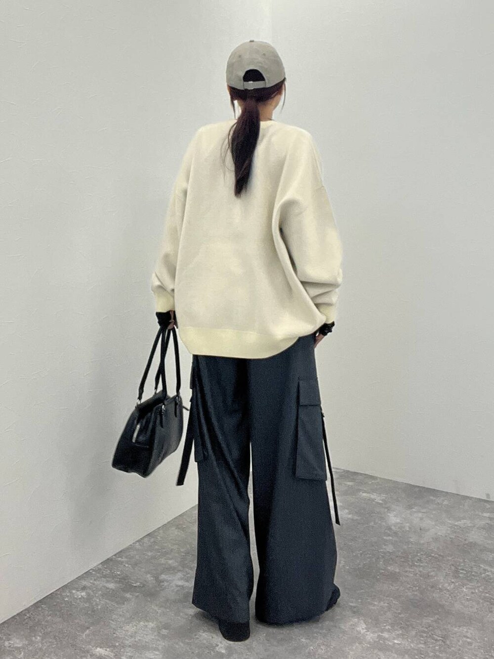 ブラック系のTシャツ/カットソー、グレー系のスラックス、ブラック系のボストンバッグを着用したレディースの秋コーディネートの4枚目の写真