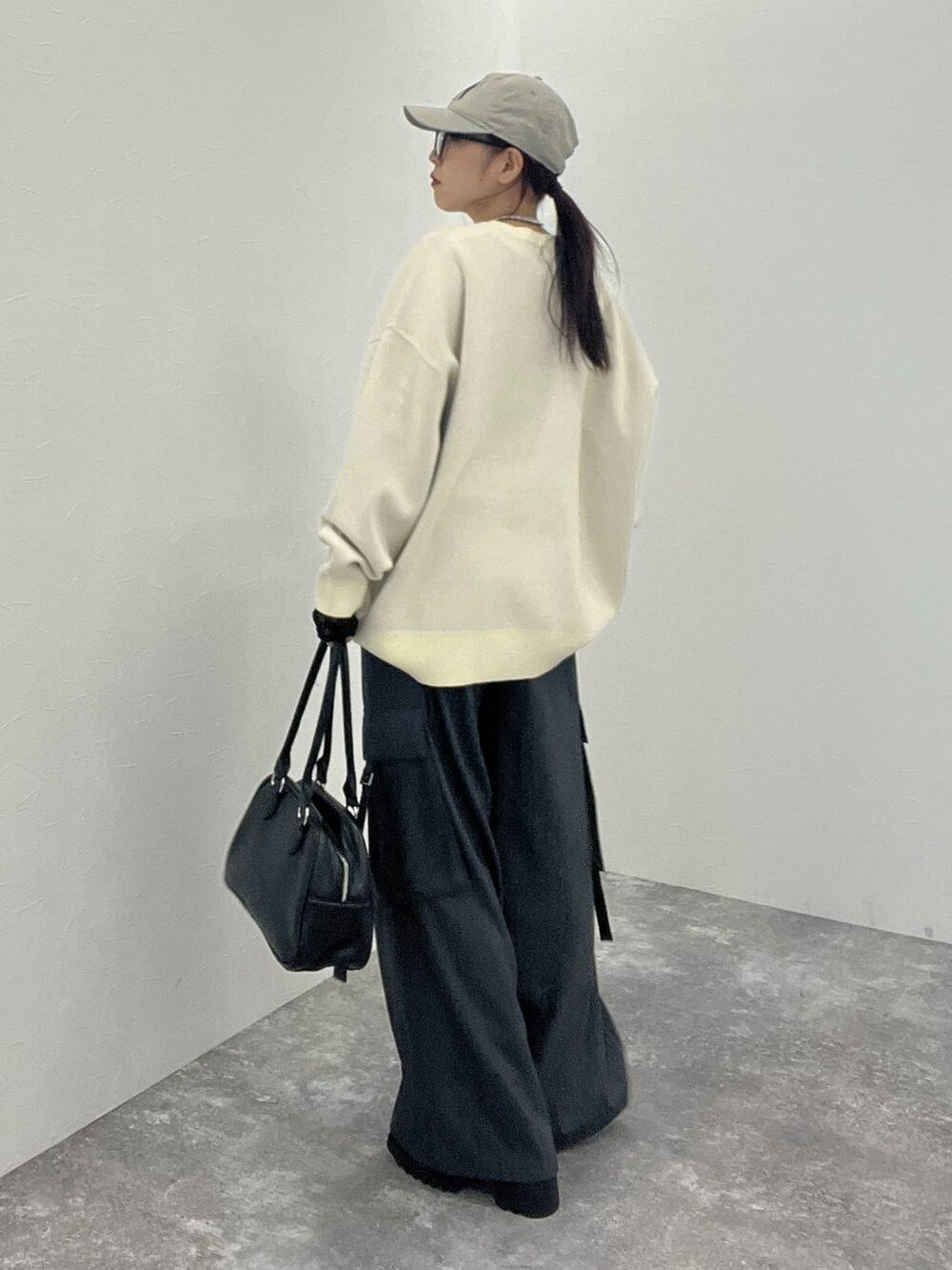 ブラック系のTシャツ/カットソー、グレー系のスラックス、ブラック系のボストンバッグを着用したレディースの秋コーディネートの5枚目の写真