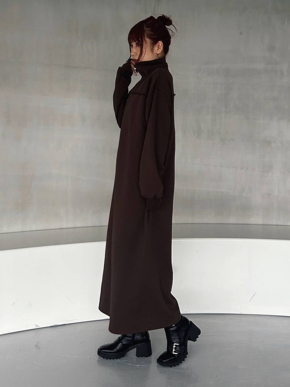 その他のハンドバッグ、ブラック系のブーツ、ブラウン系のワンピースを着用したレディースの秋コーディネートの4枚目の写真