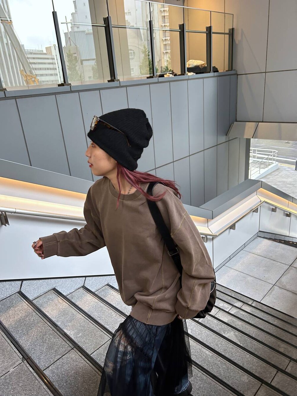 ブラウン系のスウェット、ブルー系のデニムパンツ、ブラック系のブーツを着用したレディースの秋コーディネートの4枚目の写真